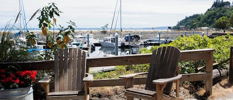 A wooden deck with Adirondack chairs overlooking a marina with boats.