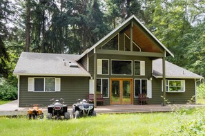 Une maison à deux étages avec une grande véranda à l’avant, une terrasse couverte et un garage.