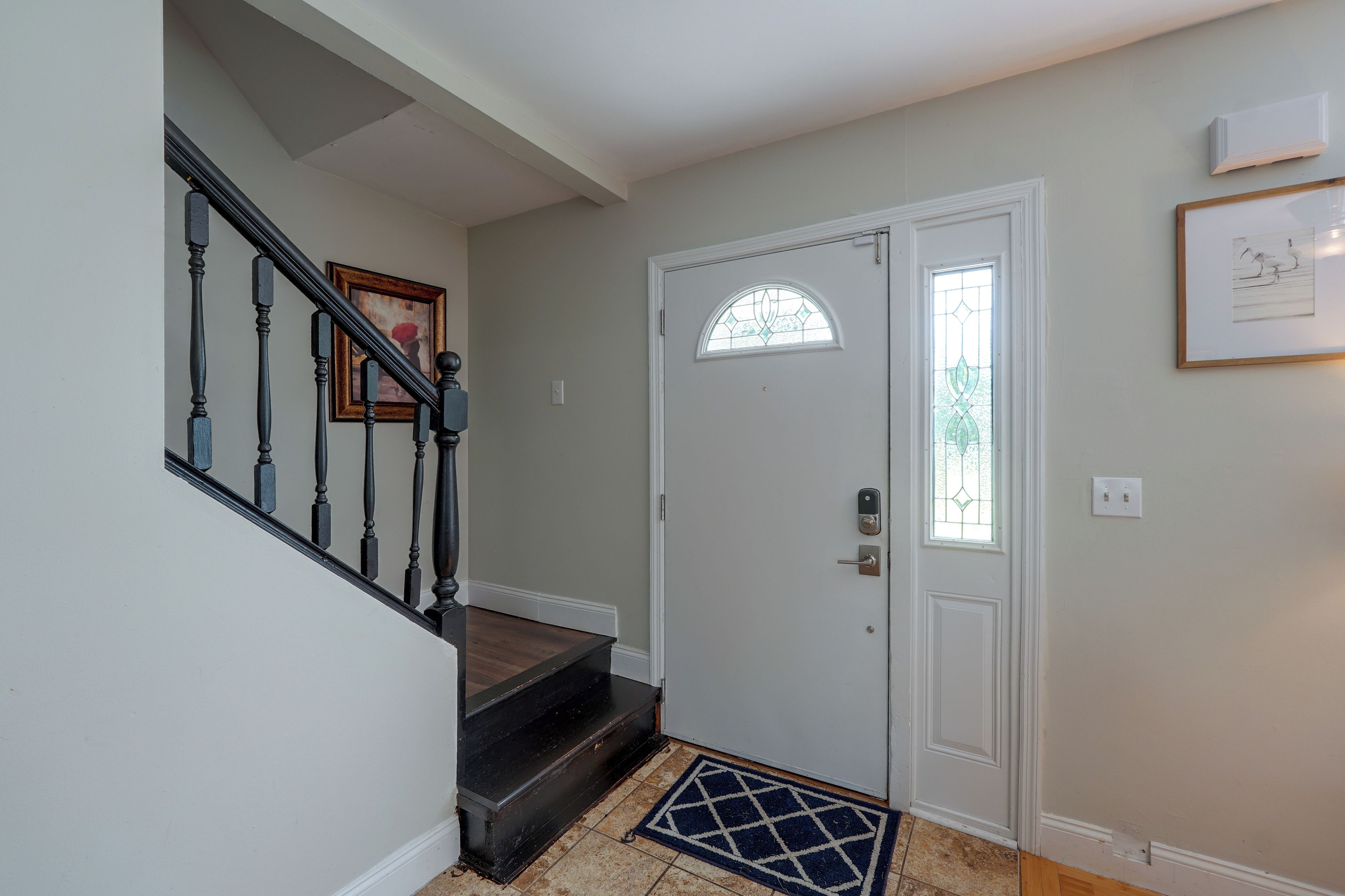 A staircase with a handrail and a door with a glass panel and a lock.