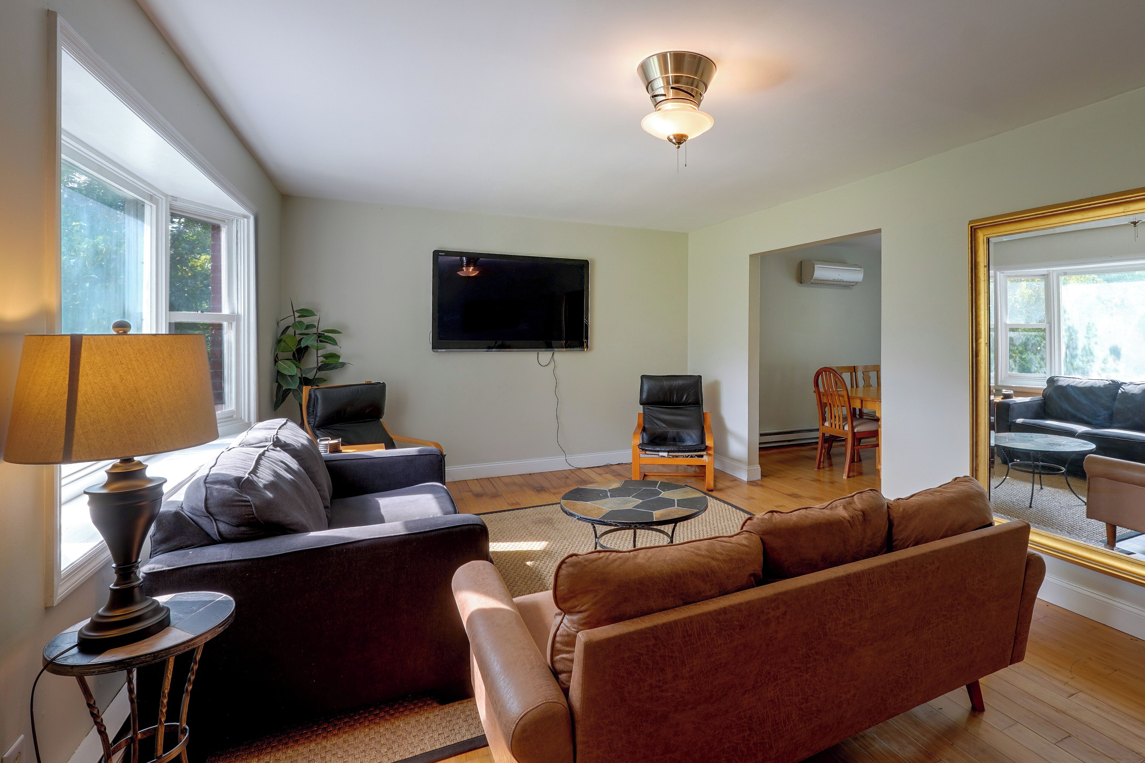 A living room with a sofa, a coffee table, a TV mounted on the wall, and a ceiling fan.