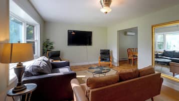 A living room with a sofa, a coffee table, a TV mounted on the wall, and a ceiling fan.