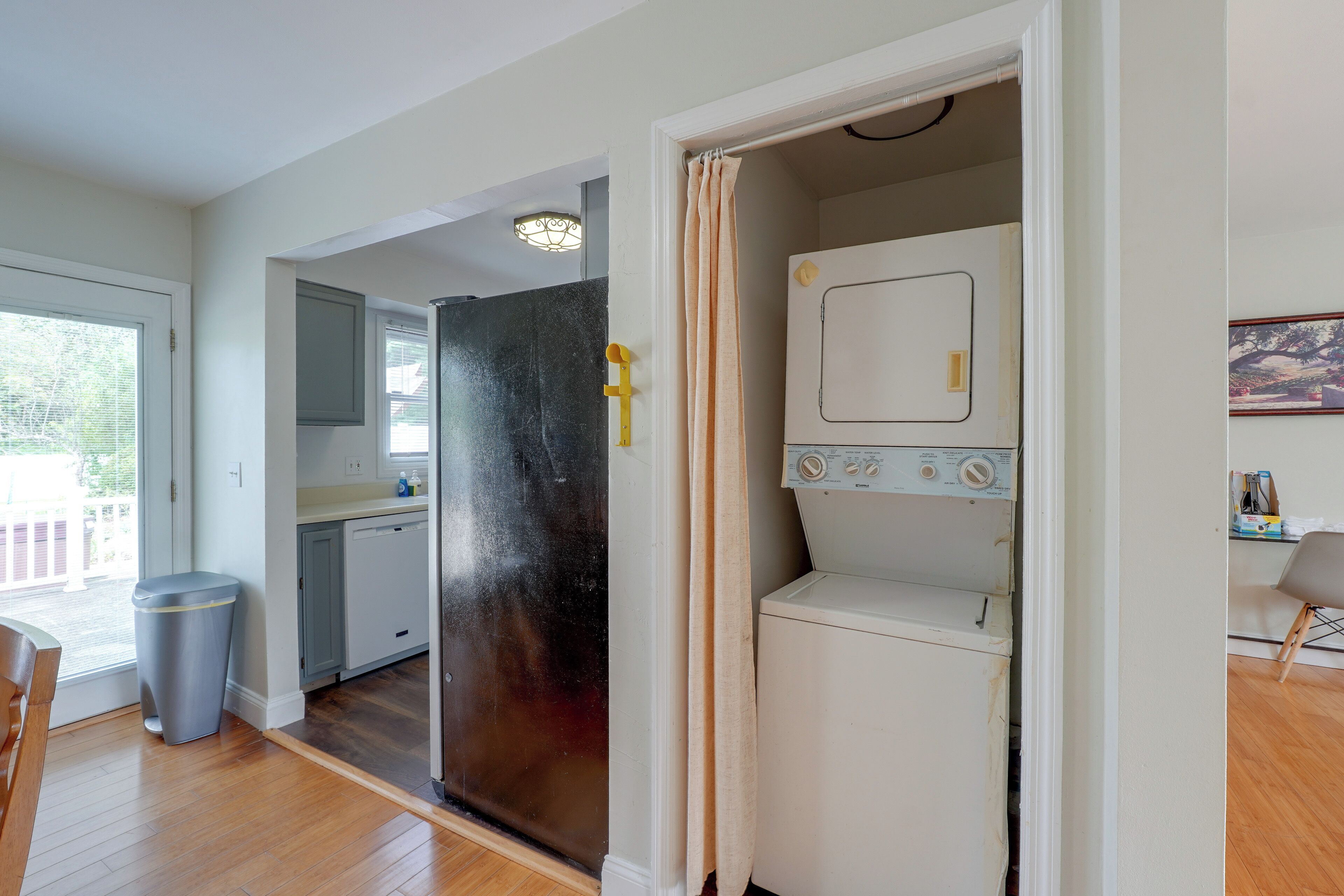 A compact kitchen with a dishwasher, a small refrigerator, and a window with blinds.
