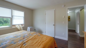 A bedroom with a bed, a window, a heater, and a door leading to another room. - Hudson Valley Duplex: Hike, Sip + Explore! (Highland)