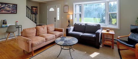 A living room with a sofa, a coffee table, and a chair. There is a staircase leading to another room.