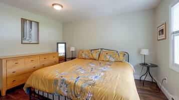 A bedroom with a bed, bedside tables, a dresser, a window, and a ceiling light.