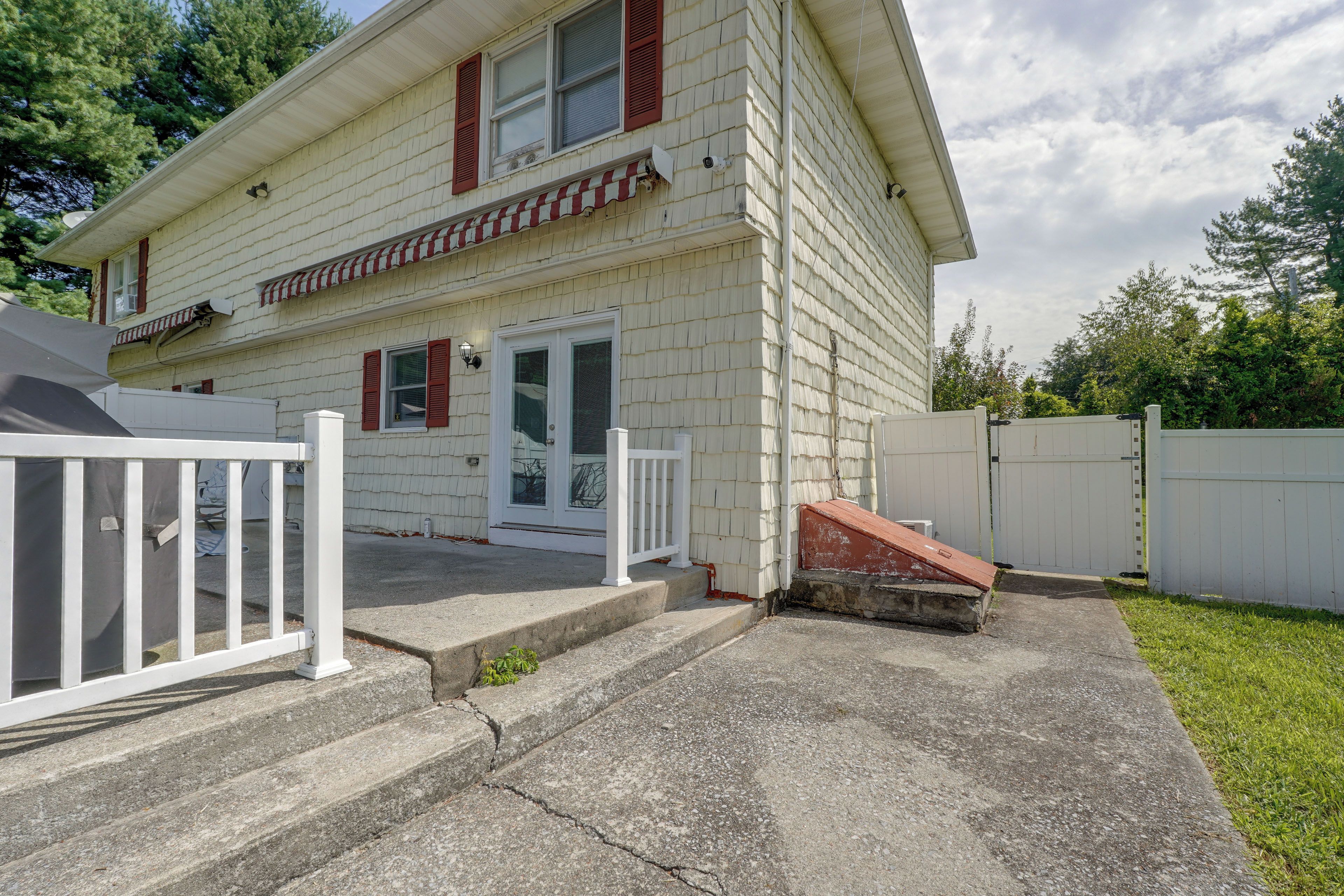 A two-story house with a front porch, a white fence, and a small front yard.