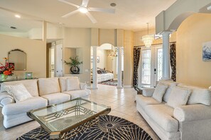 A spacious living room with a glass coffee table, beige sofas, and a chandelier. - Great for Groups! Canalfront Cape Coral Getaway (Cape Coral)