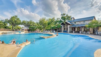 Piscina com um edifício de fachada em pedra ao fundo.