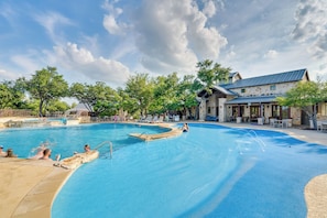 Piscina com um edifício de fachada em pedra ao fundo.