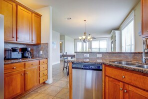 A kitchen with wooden cabinets, a dishwasher, and a granite countertop. - Lake Travis Escape at The Hollows (Leander)