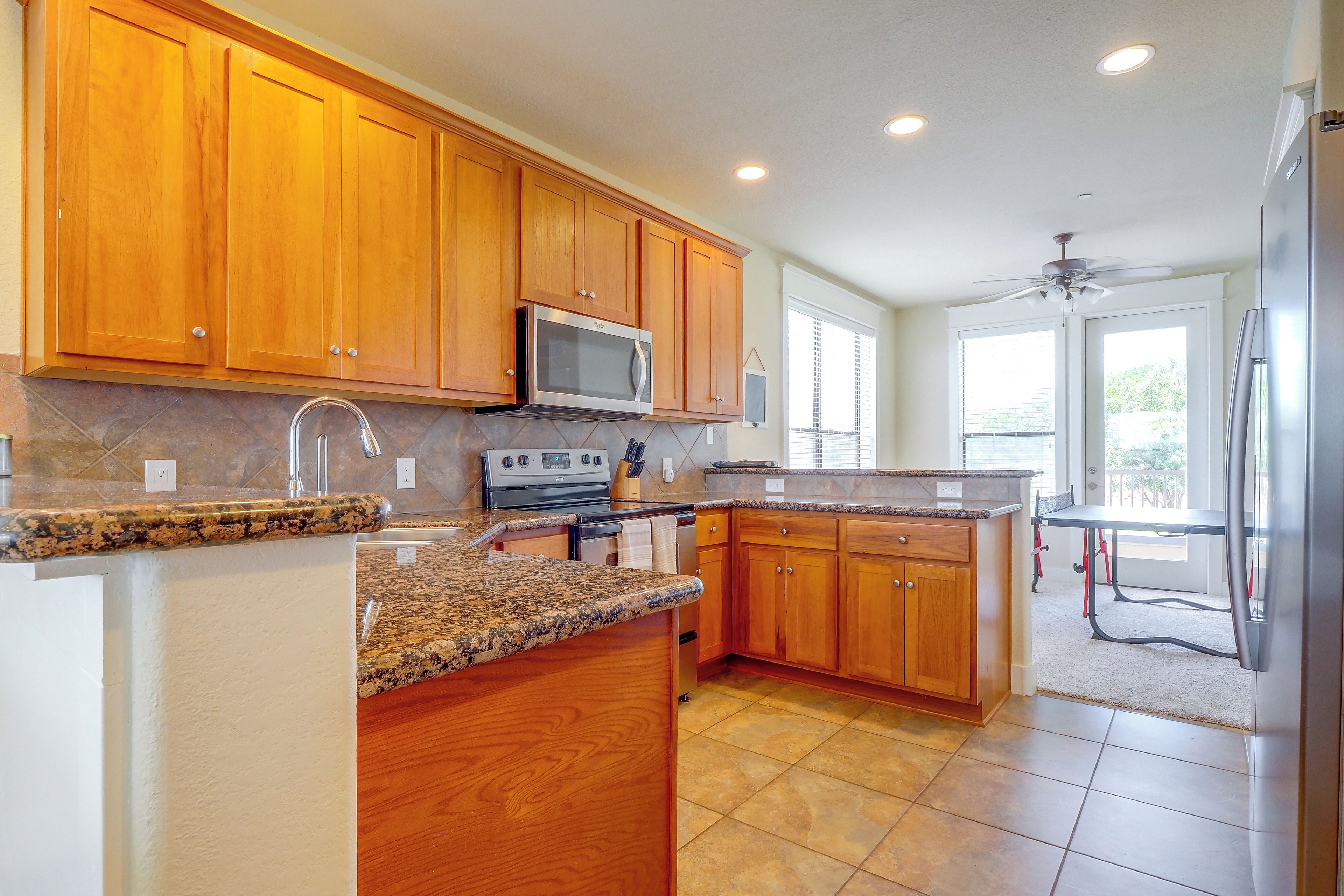 A kitchen with wooden cabinets, a microwave, a stove, and a refrigerator.
