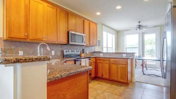 A kitchen with wooden cabinets, a microwave, a stove, and a refrigerator.