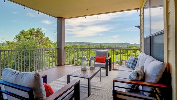 Un balcón con sofá, silla y mesa, con vista a un paisaje verde.
