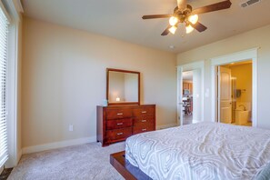 A bedroom with a bed, a dresser, a mirror, and a ceiling fan. - Lake Travis Escape at The Hollows (Leander)
