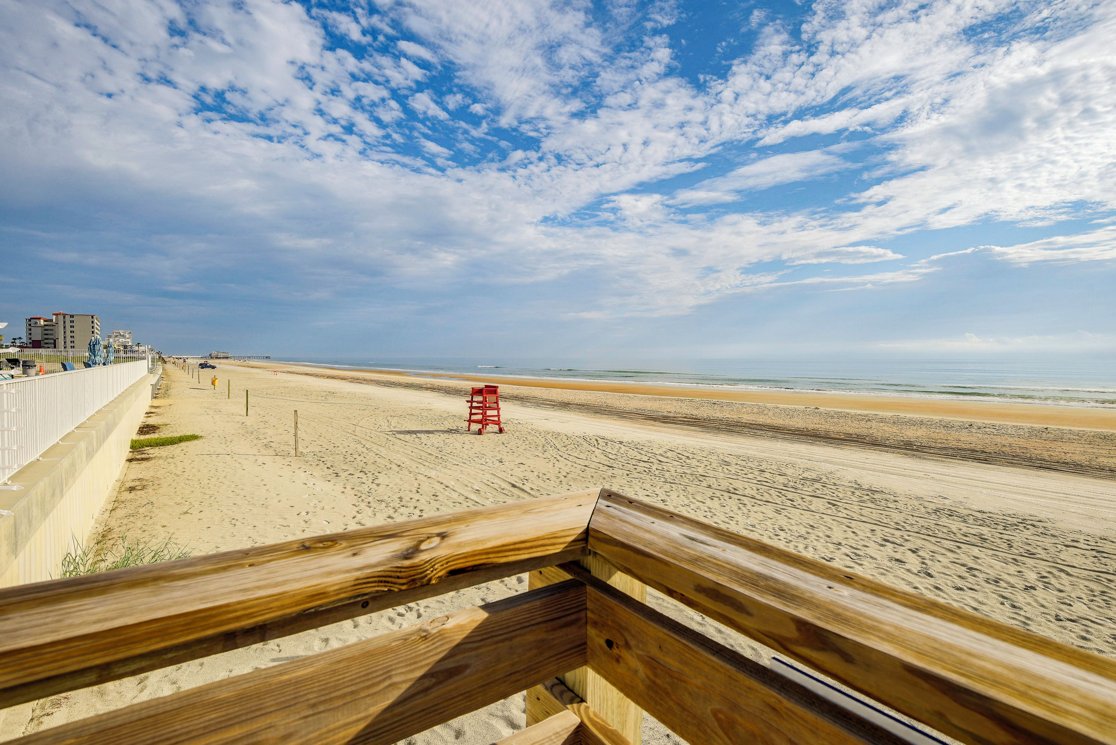 A beach with a wooden walkway and a lifeguard stand.