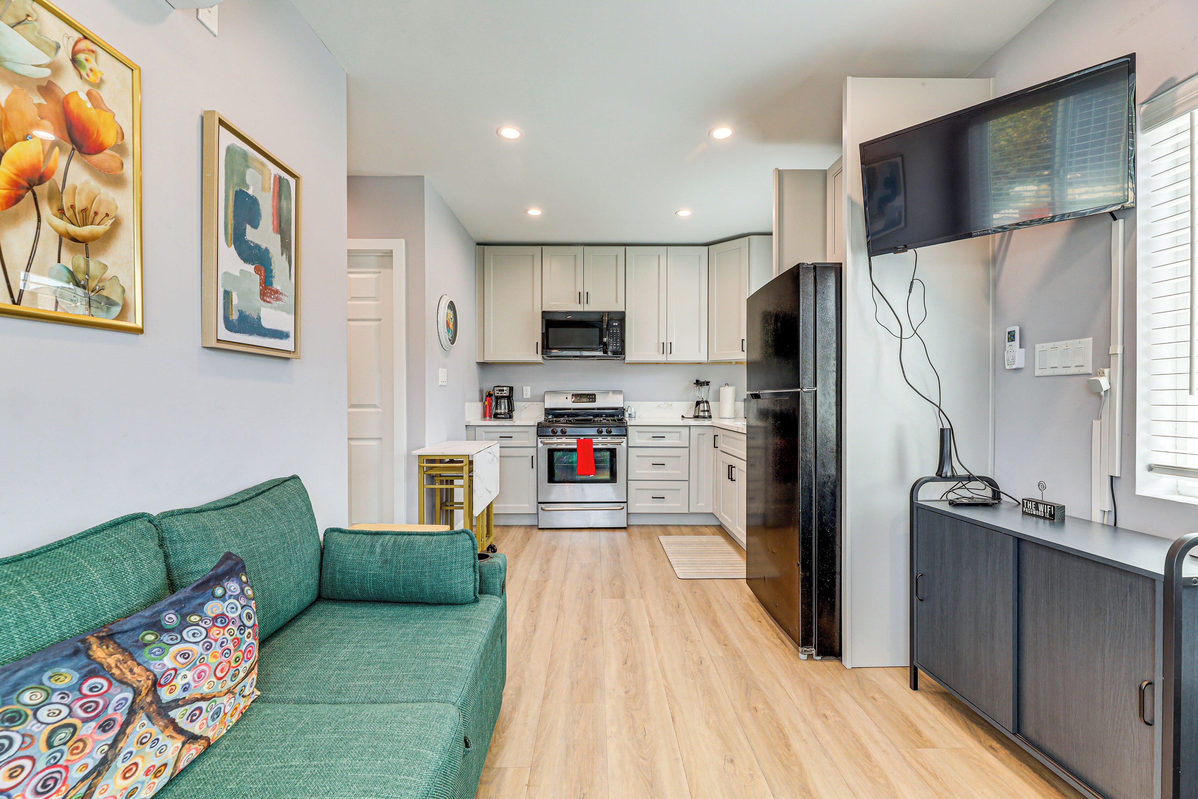A modern kitchen with white cabinets, a stainless steel refrigerator, and a microwave.