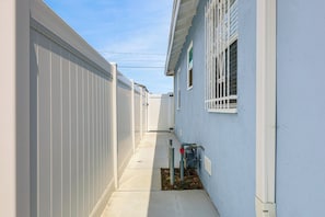 A narrow alleyway between two buildings with white exterior walls and a clear sky above.