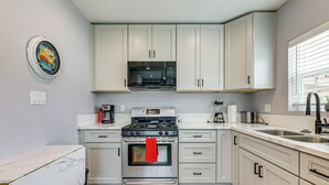 A modern kitchen with white cabinets, a stainless steel stove, and a microwave above it.