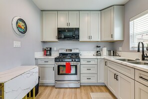 A modern kitchen with white cabinets, a stainless steel stove, and a microwave above it.