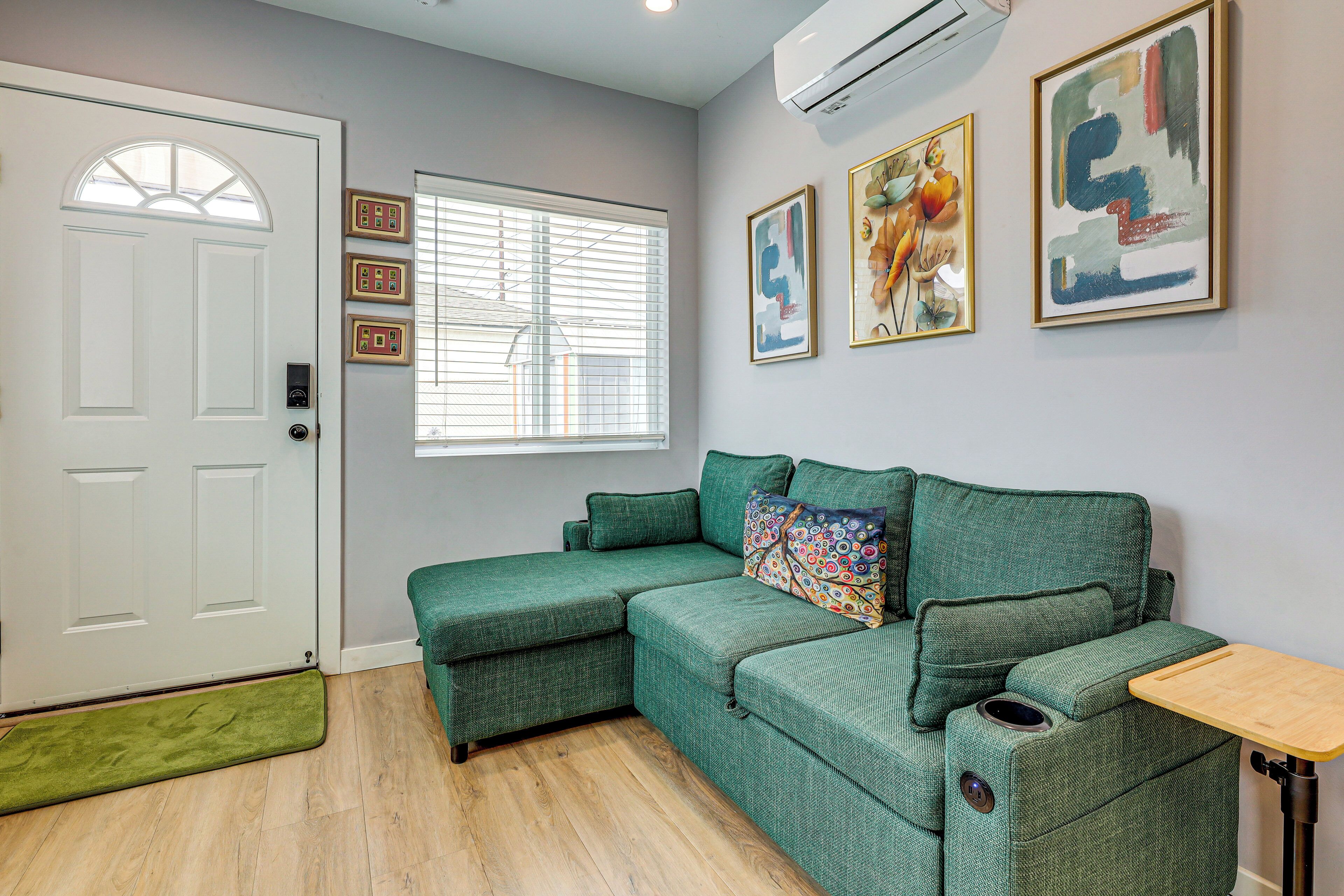 A room with a green sofa, a white door, and a window with blinds.