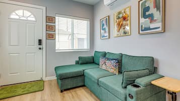 A room with a green sofa, a white door, and a window with blinds.