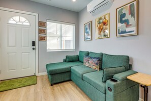 A room with a green sofa, a white door, and a window with blinds. - Spacious, Cozy Rear House Near LAX (Compton)