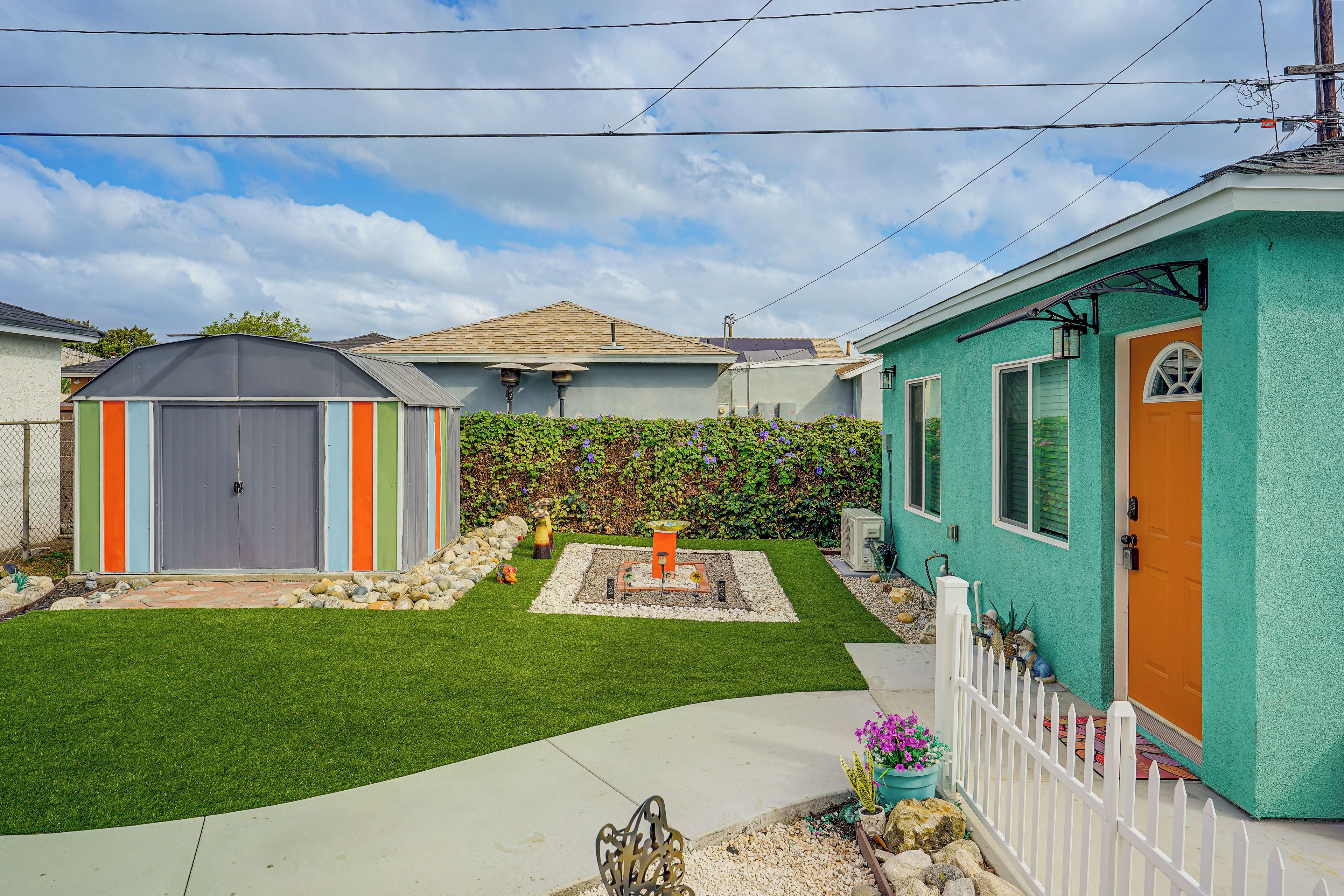 A residential property with a fenced yard, a small shed, and a house with a green exterior.