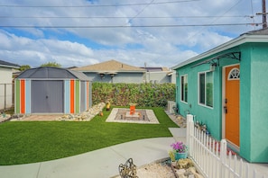 A residential property with a fenced yard, a small shed, and a house with a green exterior.