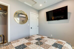 A bedroom with a bed, a television mounted on the wall, a door, and a wall-mounted air conditioning unit. - Spacious, Cozy Rear House Near LAX (Compton)
