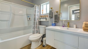 A bathroom with a bathtub, toilet, sink, and mirror.