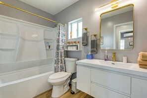 A bathroom with a bathtub, toilet, sink, and mirror.