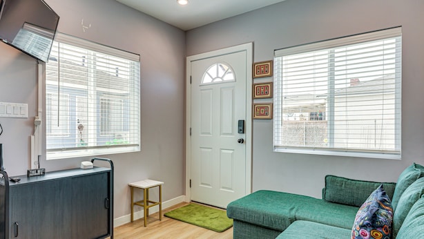A room with a grey sofa, a small table, a cabinet, and a door with a window.