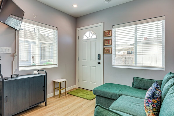 A room with a grey sofa, a small table, a cabinet, and a door with a window.