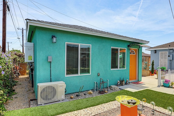 A single-story house with a green exterior, a front door, and a visible air conditioning unit.