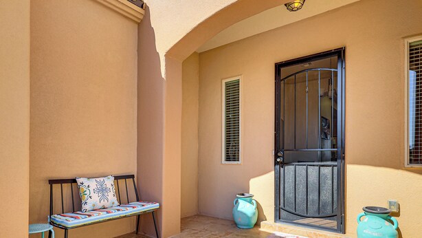 A sunlit outdoor area with a bench, a door, and two vases. - Las Cruces Oasis: Patio, Hot Tub + Mtn Views (Las Cruces)