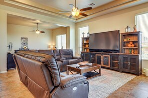 A spacious living room with a large flat-screen TV, leather sofas, and a ceiling fan. - Las Cruces Oasis: Patio, Hot Tub + Mtn Views (Las Cruces)