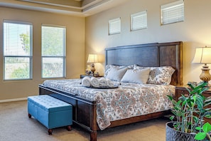 A bedroom with a large bed, a nightstand, a lamp, a bench, and a potted plant. - Las Cruces Oasis: Patio, Hot Tub + Mtn Views (Las Cruces)