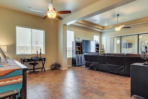 A spacious living room with a fireplace, a large sofa, and a television. - Las Cruces Oasis: Patio, Hot Tub + Mtn Views (Las Cruces)