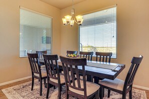 A dining area with a dark wooden table, six chairs, and a chandelier. - Las Cruces Oasis: Patio, Hot Tub + Mtn Views (Las Cruces)
