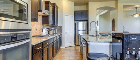 A modern kitchen with stainless steel appliances, a granite countertop, and a built-in oven.