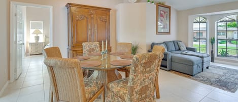 A dining area with a round table, chairs, and a chandelier.