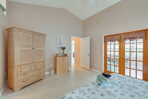 Ein Schlafzimmer mit großem Holzschrank, einem Bett mit gemustertem Überwurf und einer Glasschiebetür zu einem Außenbereich.