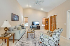 A living room with a sofa, coffee table, TV, and patterned rug. - Private Hot Tub & Dock! Hutchinson Island Retreat (Fort Pierce)
