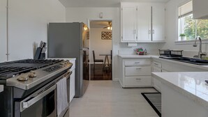 Cozinha moderna com armários brancos, fogão de aço inoxidável e forno embutido.