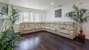 Sofá modular em sala de estar com piso de madeira e plantas em vasos.