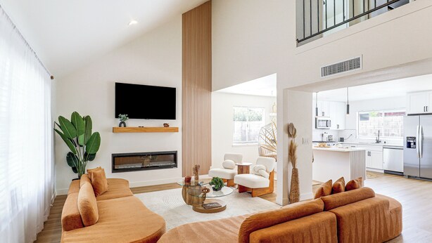 A modern living room with a large sectional sofa, a flat-screen TV, and a fireplace.