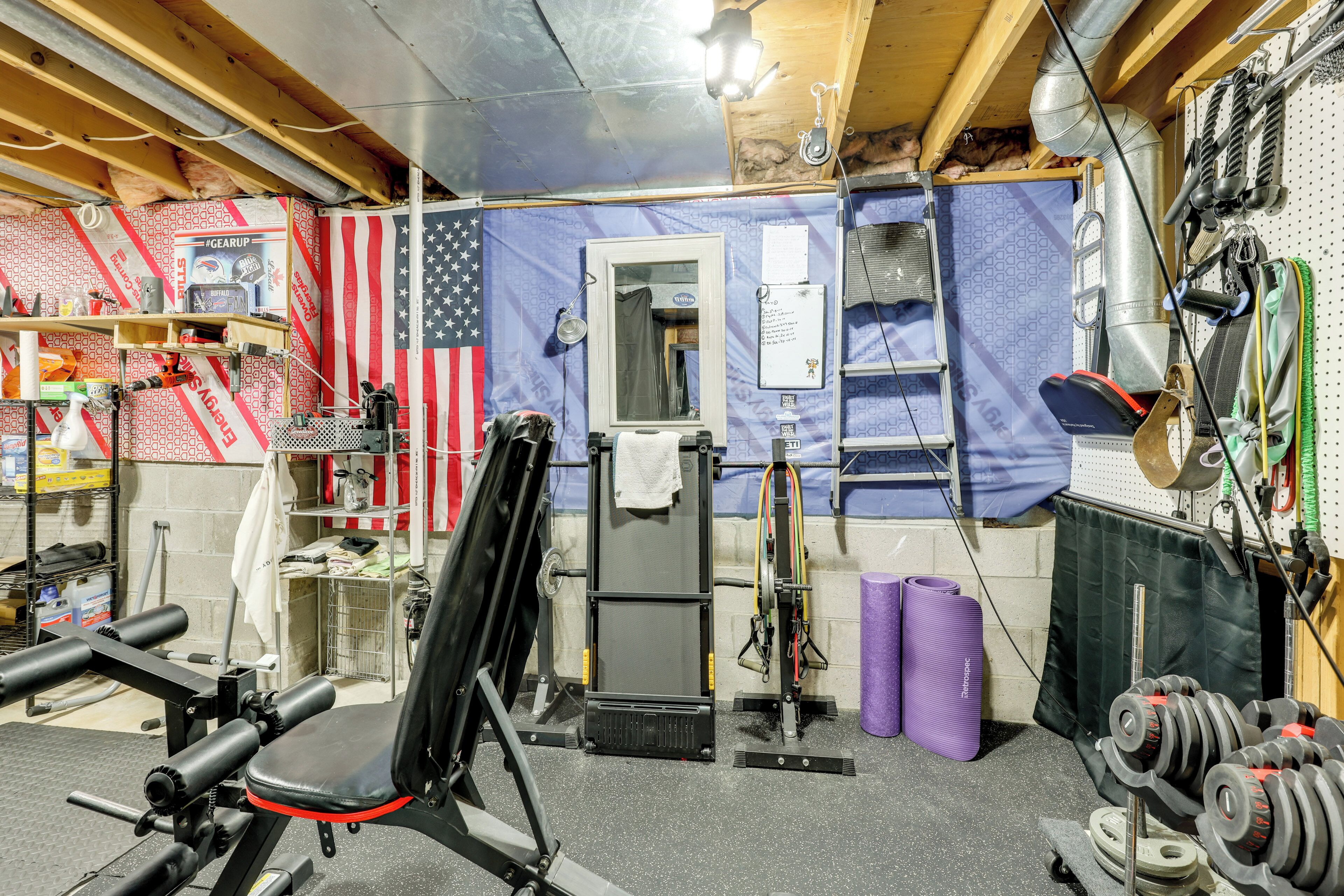 A gym with a weight bench, dumbbells, and a mirror.