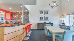 Een moderne keuken met een bar, een eettafel met stoelen en een groot raam.