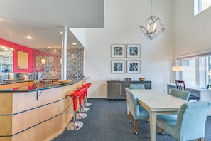 Une cuisine moderne avec un coin bar, une table à manger avec des chaises et une grande fenêtre.