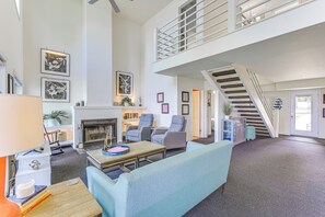 A spacious living area with a fireplace, seating, and a staircase leading to an upper level.